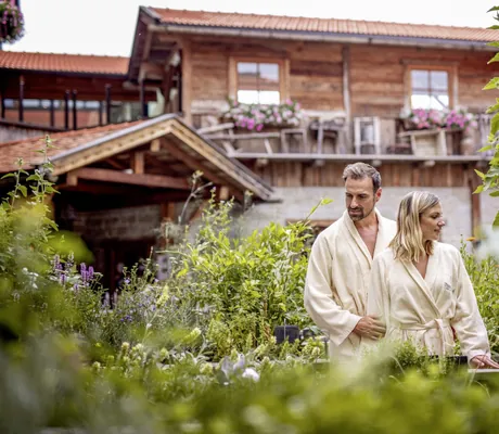 Ein Pärchen in Bademänteln erkundet den grünen Garten vor dem Hotel Brunner Hof in Arnschwang.