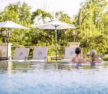 Infinitypool des Natur- und Wellnesshotels Brunner Hof in Arnschwang mit Bäumen und Sonnenschirmen.
