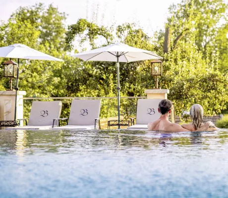 Infinitypool des Natur- und Wellnesshotels Brunner Hof in Arnschwang mit Bäumen und Sonnenschirmen.