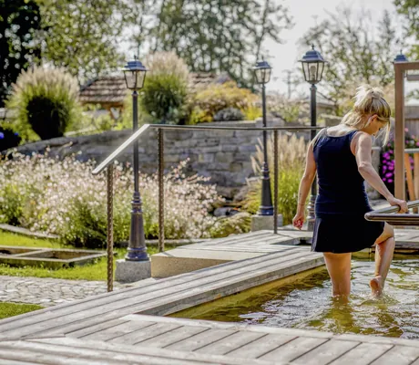 Eine Frau steigt durch ein Kneippbecken im Außenbereich des Hotels Brunner Hof in Arnschwang.