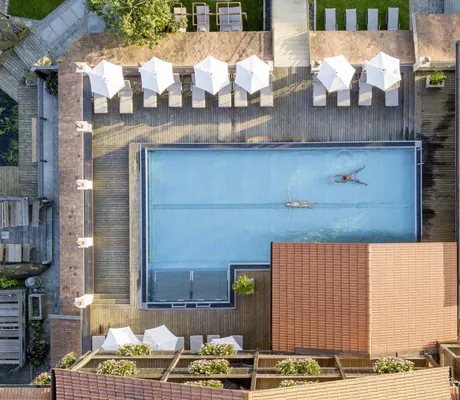 Vogelperspektive auf die Hotelanlage sowie den großzügigen Outdoor-Infinitypool des Hotel Brunner Hof im Bayerischen Wald.