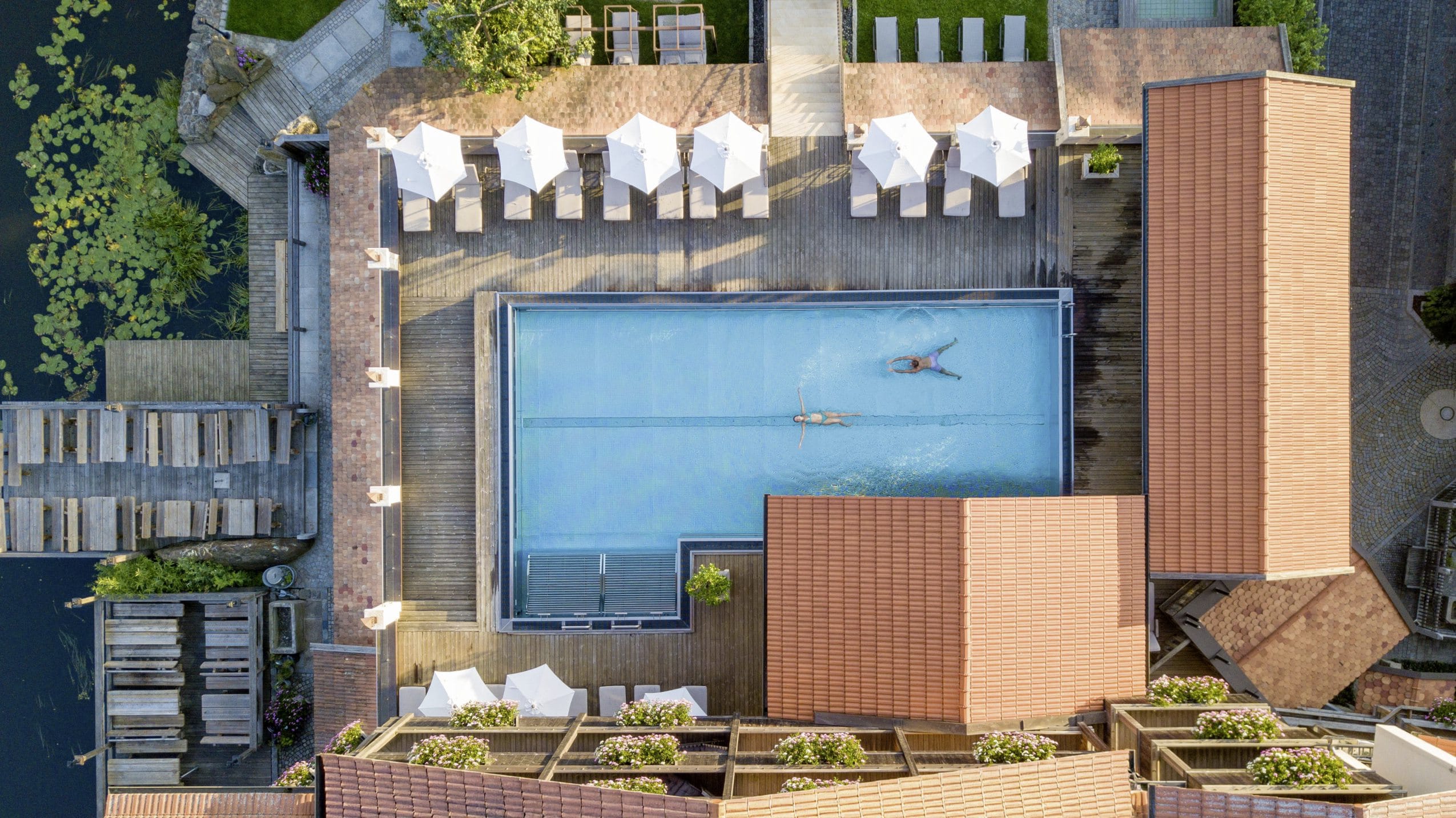 Vogelperspektive auf die Hotelanlage sowie den großzügigen Outdoor-Infinitypool des Hotel Brunner Hof im Bayerischen Wald.