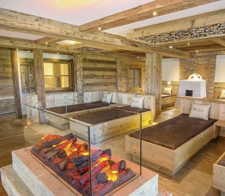 Sicht auf Holz-Liegen im Wellnessbereich, mit Effektkamin und Holz-Interieur.