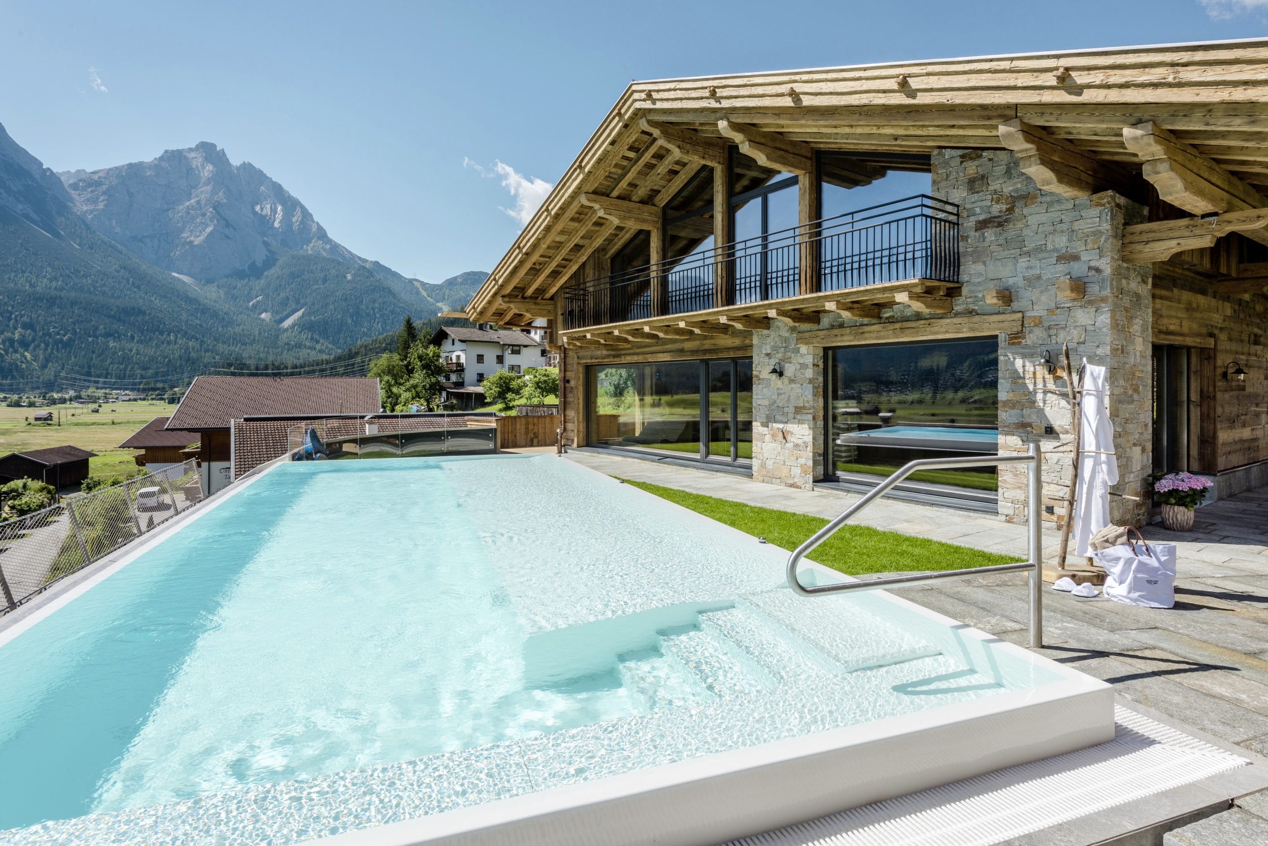 Der Außenpool des Alpine Luxury Hotel Post Lermoos mit Hotelfassade und Bergblick.