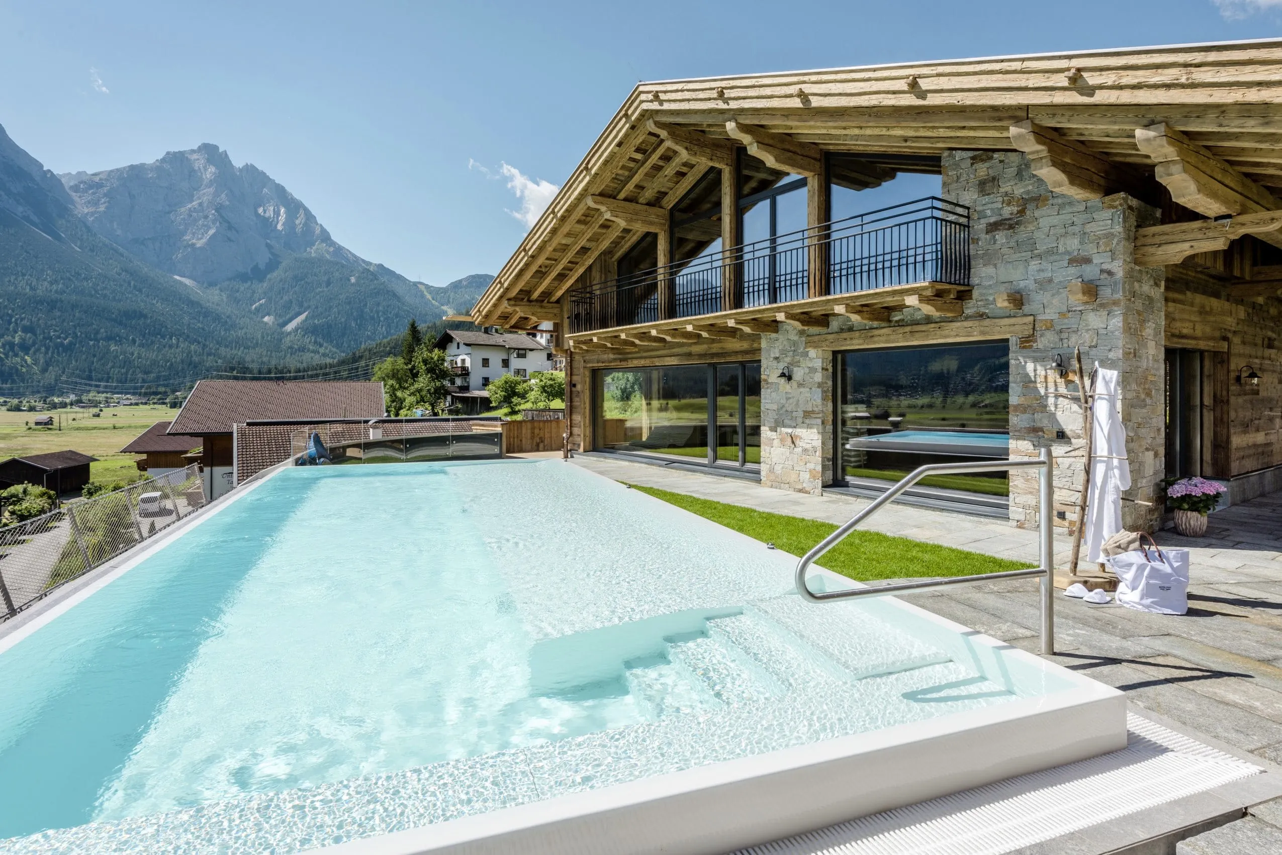 Der Außenpool des Alpine Luxury Hotel Post Lermoos mit Hotelfassade und Bergblick.