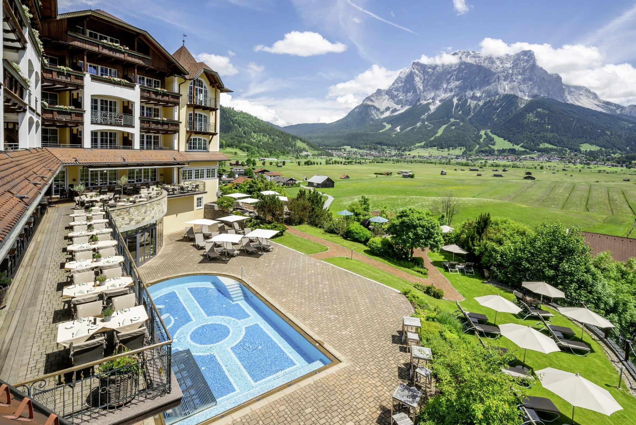 Außenaufnahme des Alpine Luxury Hotel Post Lermoos mit Outdoorpool, Bergblick und Terrasse.