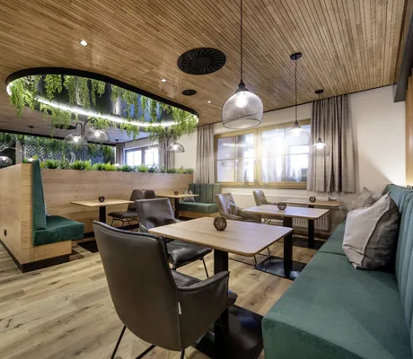 Das Cafe mit Essbereich im Landrefugium Obermüller in Untergriesbach zeigt mehrere Sitzgruppen mit Sesseln.