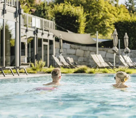 Ein Paar schwimmt im Outdoorpools des Landrefugium Obermüller in Untergriesbach, im Bayerischen Wald.