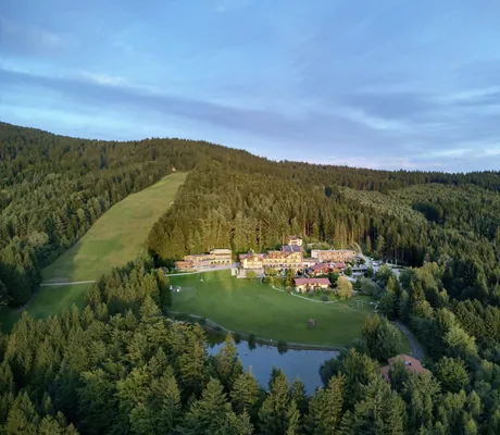 Luftaufnahme des Wellnesshotel Riedlberg inmitten von Wald und Wiesen mit großem Teich