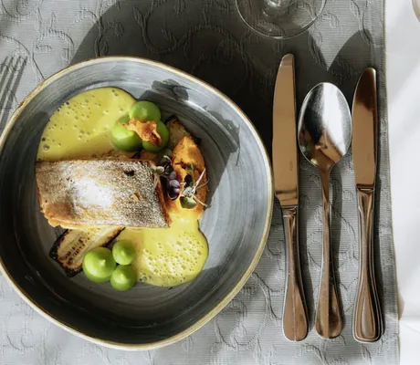 Hochwertig angerichtetes Fischgericht auf einem gedeckten Tisch im Wellnesshotel Riedlberg