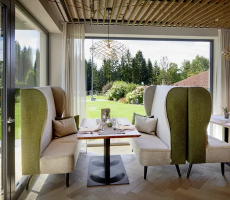Moderner Restaurantbereich im Wellnesshotel Riedlberg mit gemütlichen Sitznischen, stilvollen Designer-Leuchten und Blick ins Grüne