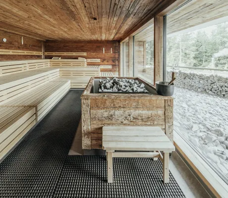 Große Sauna im Wellnesshotel Riedlberg mit Holzinterieur, Aufgussbereich im Zentrum und Blick nach draußen