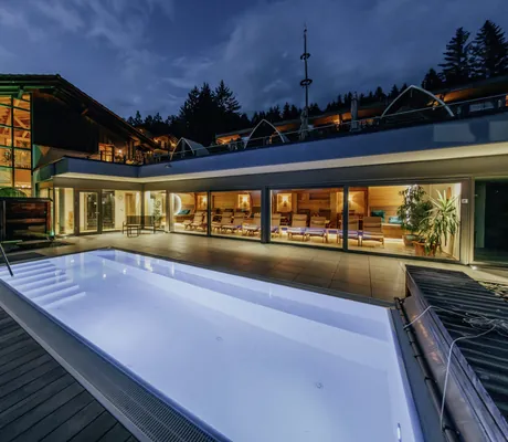 Outdoor-Solepool des Wellnesshotel Riedlberg bei Nacht, umgeben von beleuchteten Glasfronten und Blick in einen Ruheraum