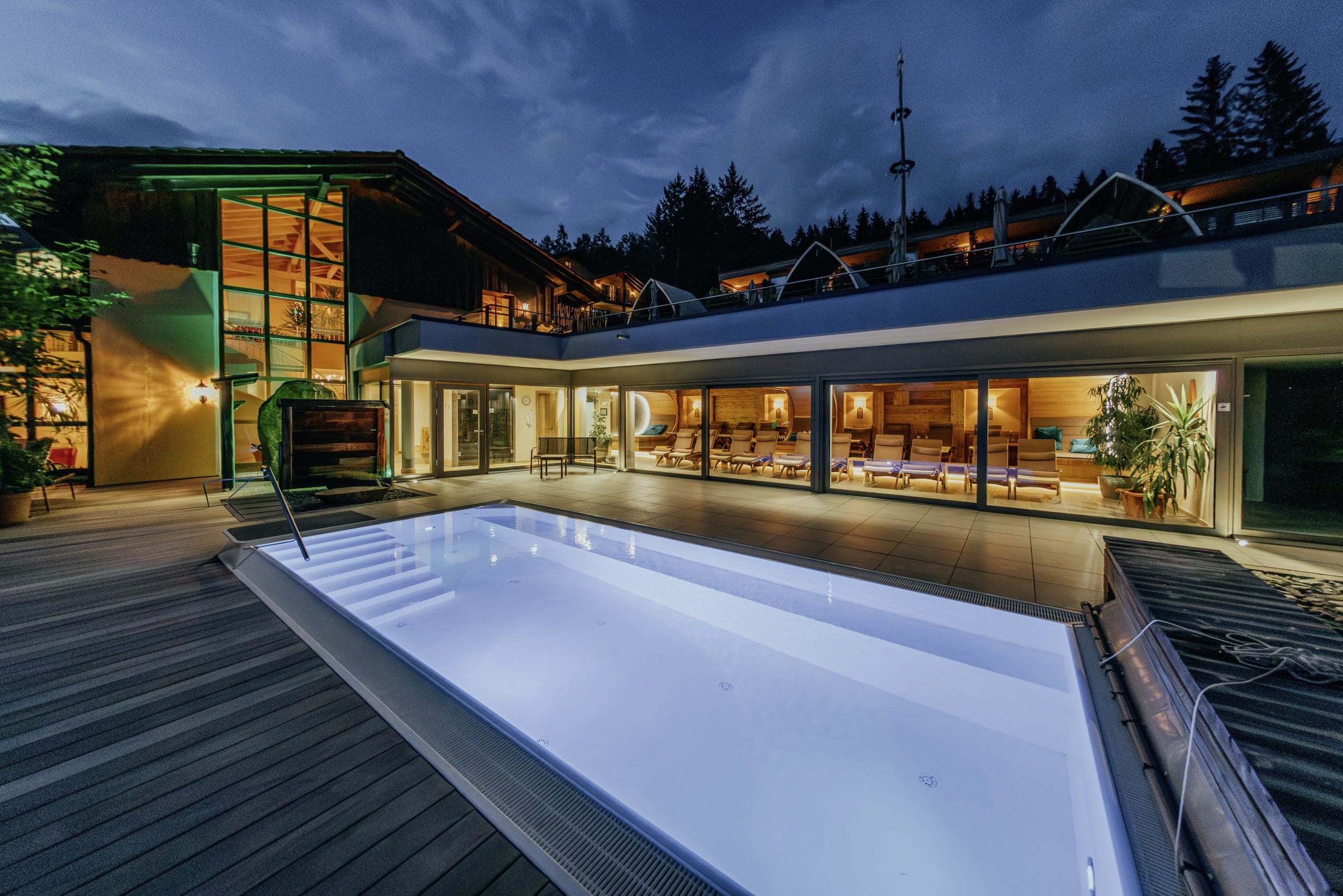Outdoor-Solepool des Wellnesshotel Riedlberg bei Nacht, umgeben von beleuchteten Glasfronten und Blick in einen Ruheraum