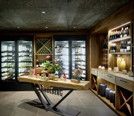 Beleuchtete Weinkühlschränke und Weinregale, Holzdetails und dekorativer Tisch im Wellnesshotel Riedlberg