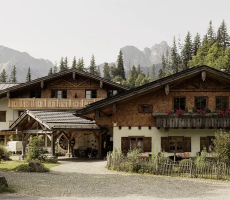 verschindelter Eingang der Schlossanger Alp mit großer Uhr vor den Felsen