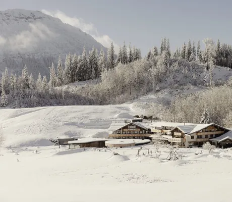 Gesamtansicht der Hotelanlage der Schlossanger Alp vor der verschneiten Bergkulisse