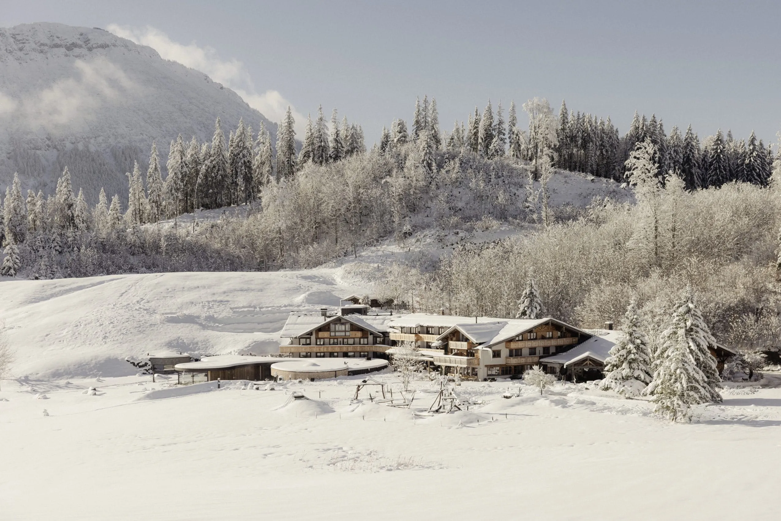 Gesamtansicht der Hotelanlage der Schlossanger Alp vor der verschneiten Bergkulisse