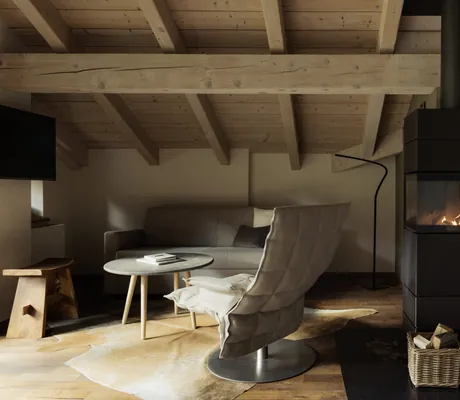 prasselnder Kamin in Loft unter Holzbalken mit beigem Drehsessel in der Schlossanger Alp