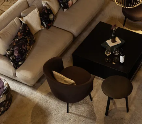 beiges großes Sofa und braune Sessel gruppiert um einen schwarzen Couchtisch in der Schlossanger Alp
