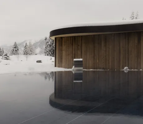 Outdoorpool mitten im Schnee vor rundem Spa-Gebäude in der Schlossanger Alp