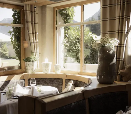 runde Sitzecke im Restaurant der Schlossanger Alp mit großer Vase mit Margheriten