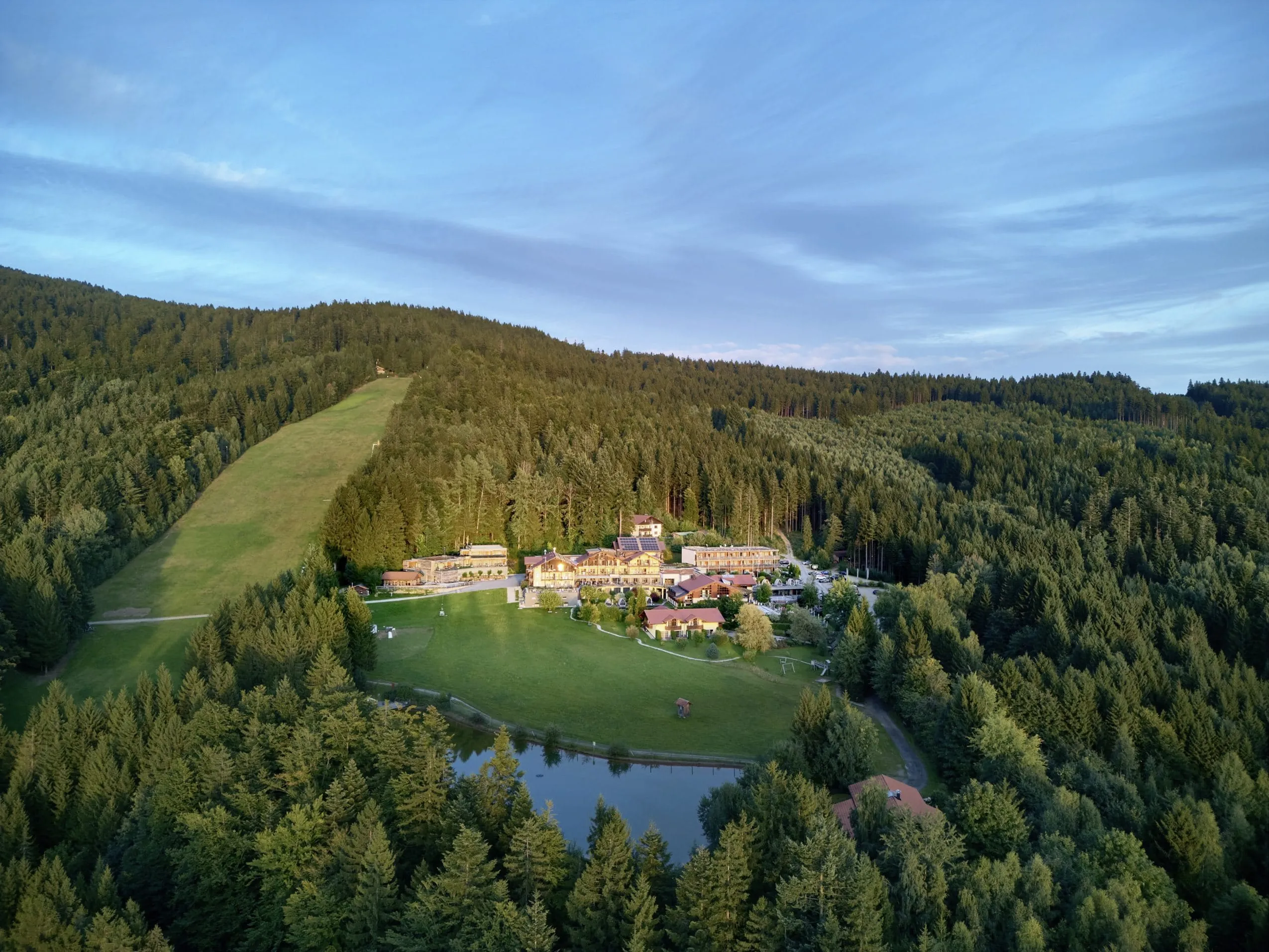 Luftaufnahme des Wellnesshotel Riedlberg inmitten von Wald und Wiesen mit gro&szlig;em Teich