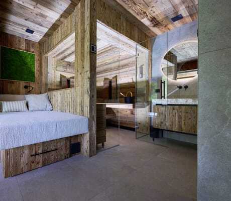 Modern eingerichteter Bereich der Ziegelberg Chalets mit Holzwänden, einer gemütlichen Sitzbank, Sauna und rundem Spiegel über Stein-Waschbecken