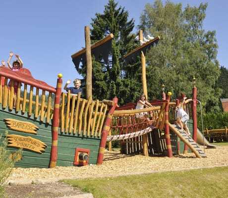 Kinder spielen im Sommer auf dem Abenteuerspielplatz des Hotel Bareiss mit großem Piratenschiff