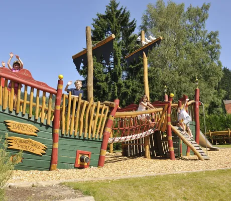 Kinder spielen im Sommer auf dem Abenteuerspielplatz des Hotel Bareiss mit großem Piratenschiff