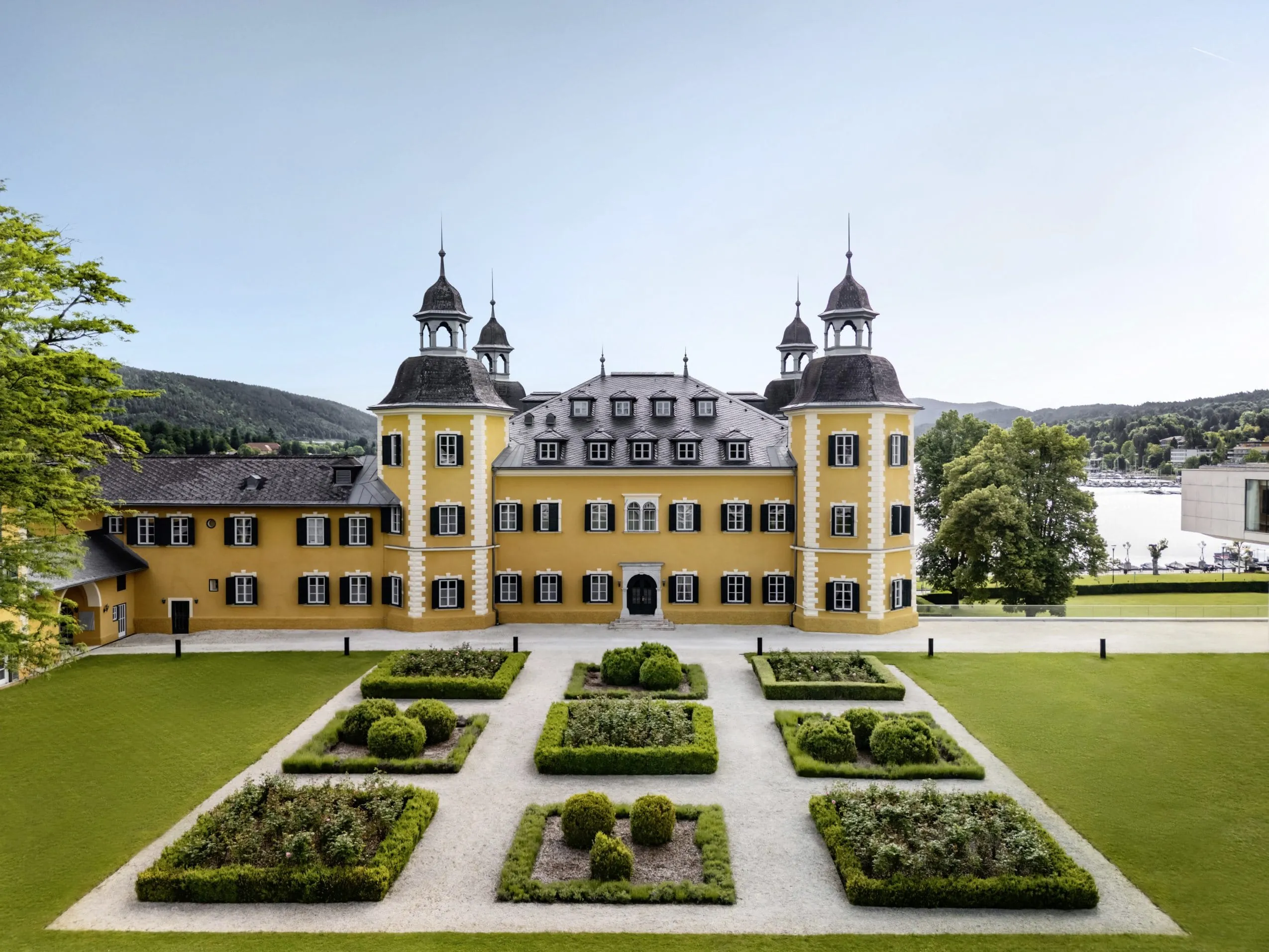 Außenbereich des Falkensteiner Schlosshotel Velden mit grüner Gartenanlage und imposanten Hotelfassaden.