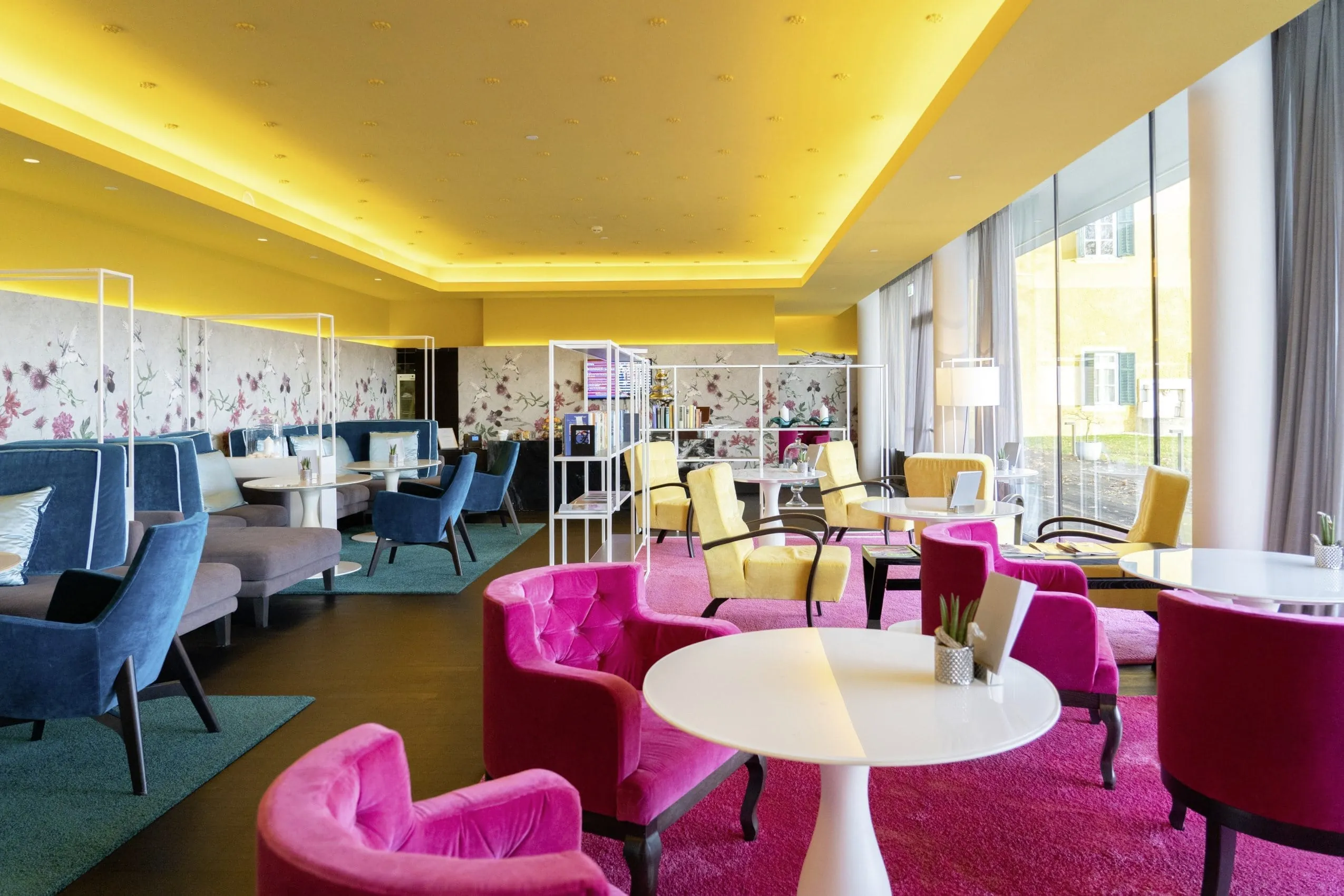Die Lobby im Falkensteiner Schlosshotel Velden mit bunten Ohrensesseln und Teppichen lädt zum Entspannen ein.
