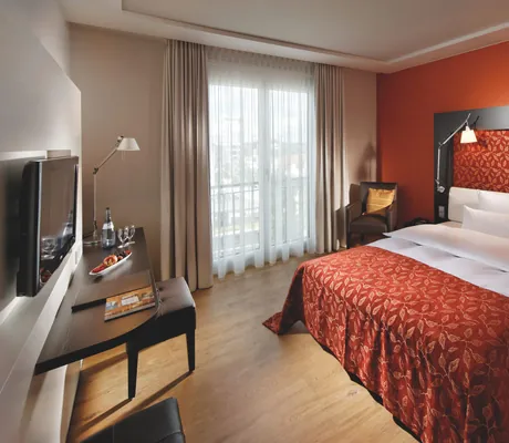 Ein klassisches Zimmer mit kaminrotem Bettbezug im Parkhotel Stuttgart-Messe Airport.