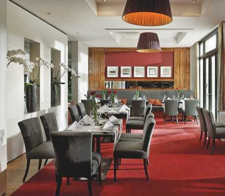 Blick ins Restaurant im Parkhotel Stuttgart-Messe Airport mit rotem Teppich und weißen Orchideen.