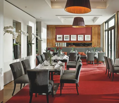 Blick ins Restaurant im Parkhotel Stuttgart-Messe Airport mit rotem Teppich und weißen Orchideen.