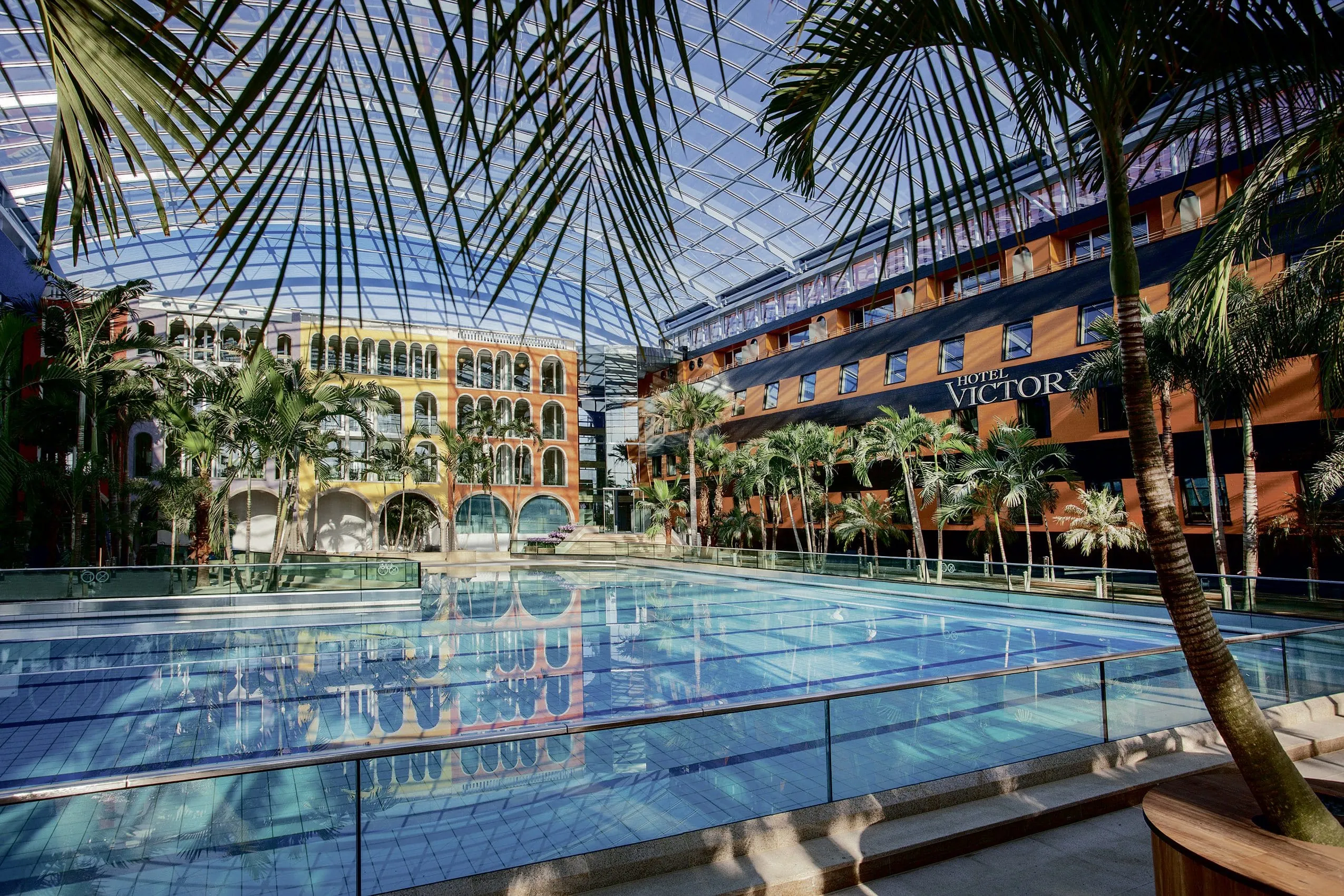 Poolbecken "Wellenbad" in der Therme Erding mit Hotel Victory und Palmen.
