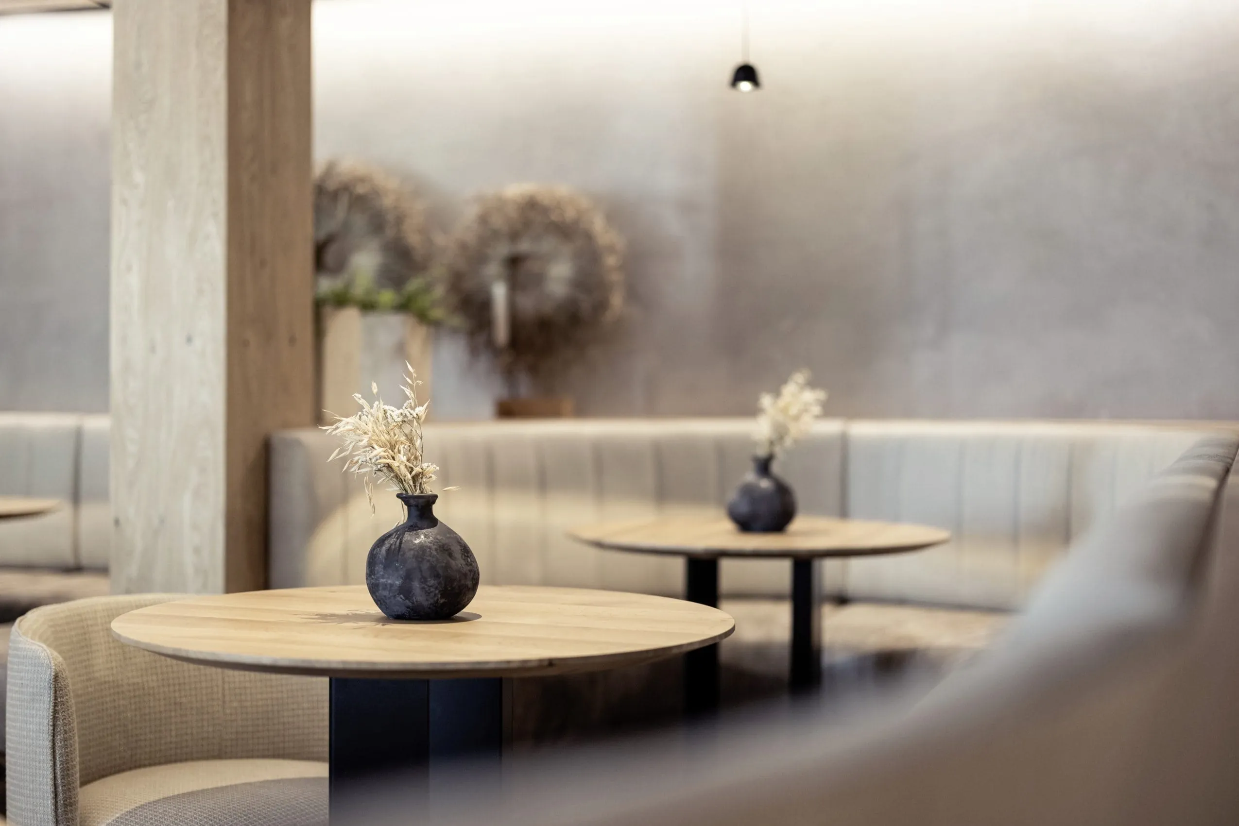 Blick auf die Lobby im Hotel Winkler mit eleganten Holztischen und beigefarbenen Sesseln.
