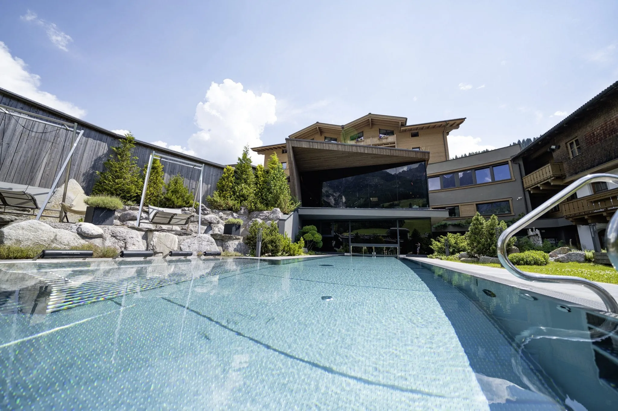 Der Pool mit Hotelfassade im Good Life Resort Riederalm.