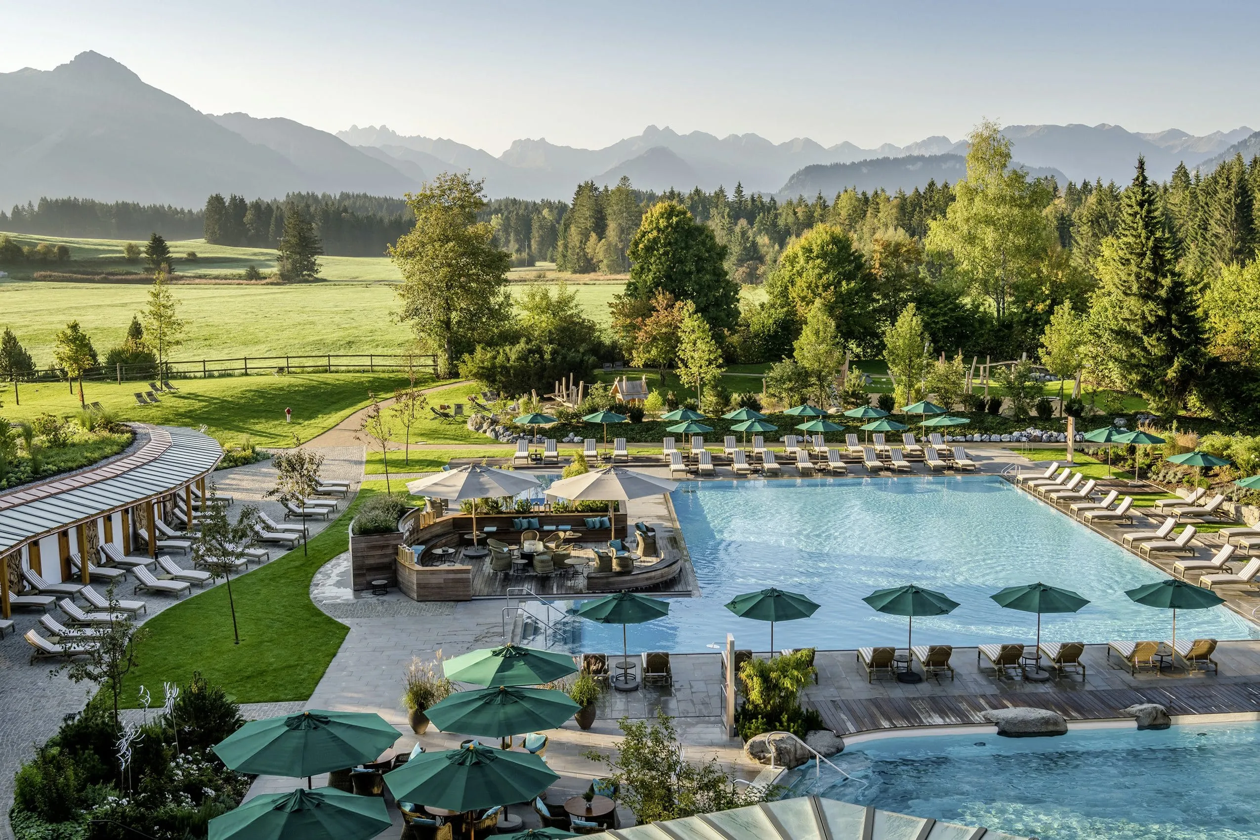 Die Außenanlage mit Poollandschaft, eingebettet im Grünen, im Sonnenalp Resort.