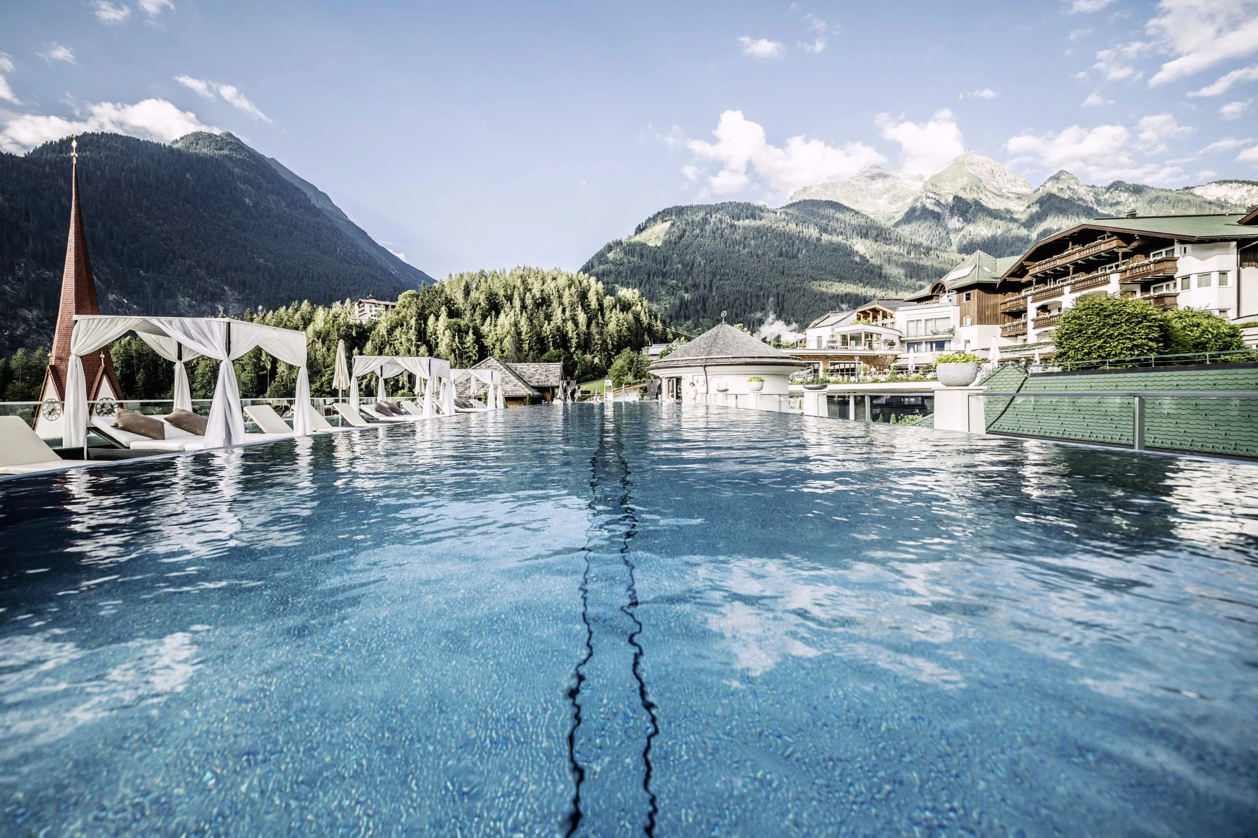 Der Infinitypool im STOCK resort in Ofterschwang vor malerischer Kulisse mit grünen Berghängen.