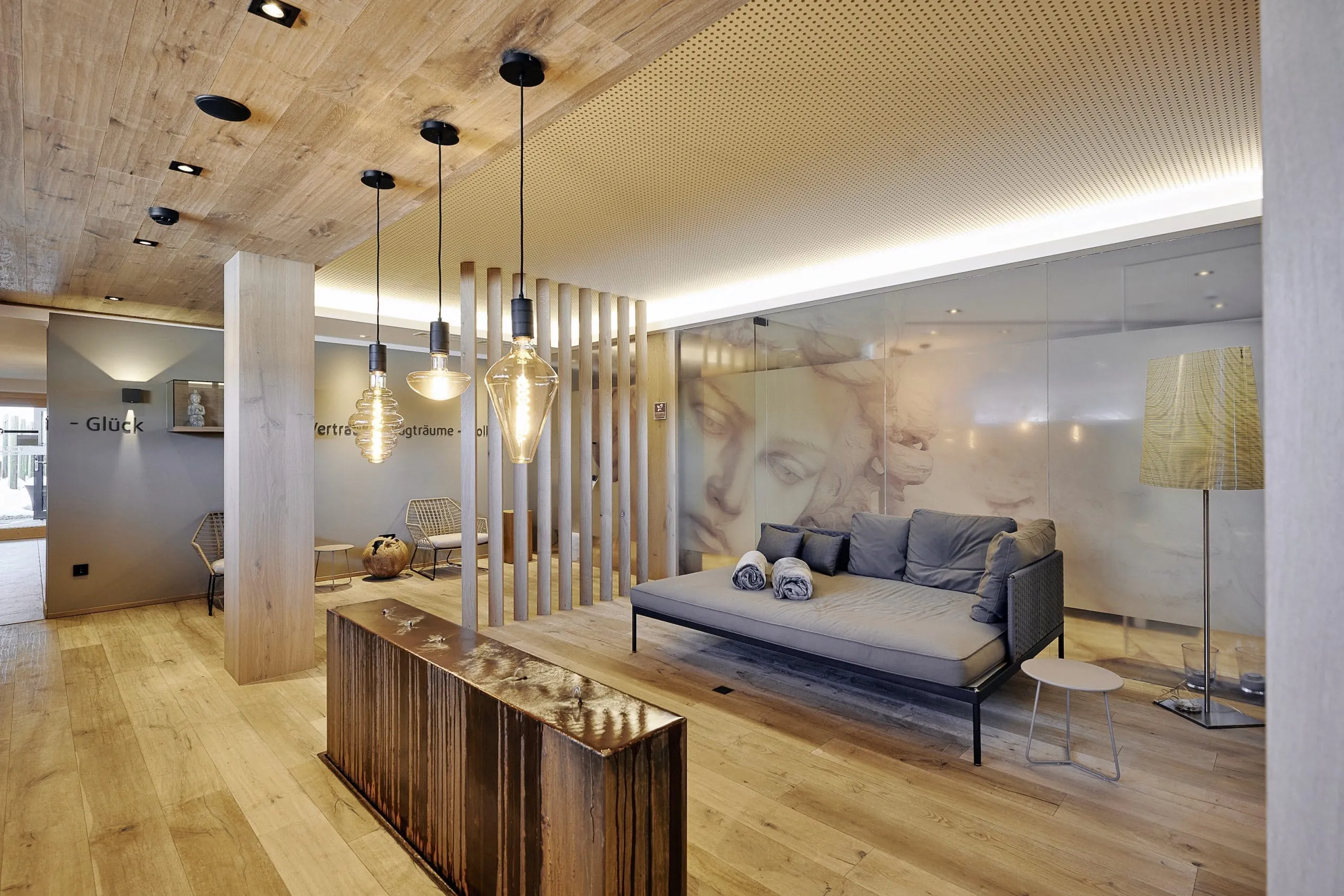 Blick in den stilvollen Spabereich mit bequemen Sofa und eleganten Deckenleuchten.