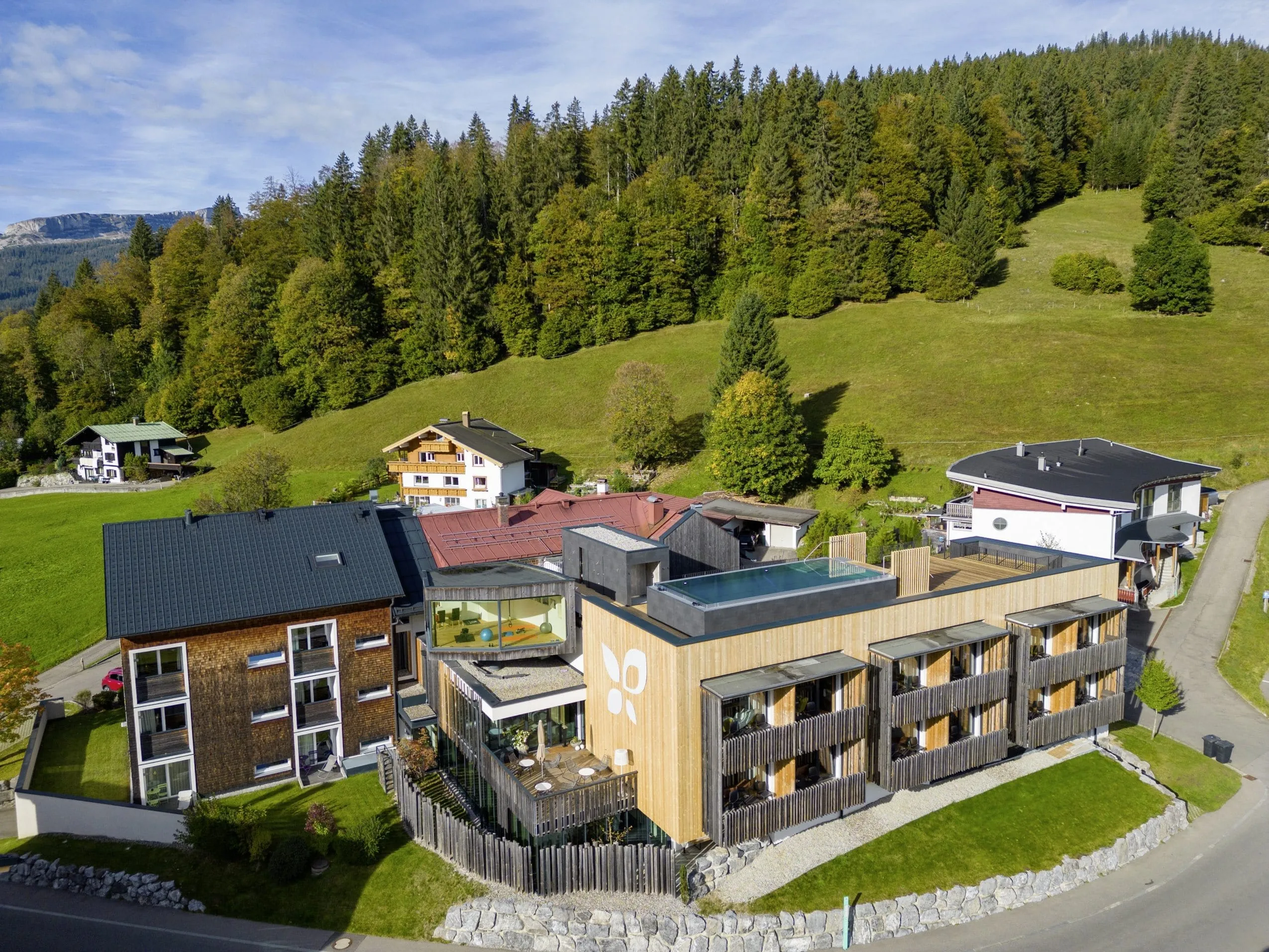 Die Au&szlig;enfassade des Genuss- und Aktivhotels Sonnenburg mit gr&uuml;nen Bergh&auml;ngen im Hintergrund.