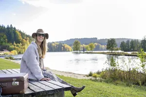 Der Rannasee als besonderes Erlebnis im Landrefugium Obermüller: Eine Frau sitzt mit mit Hut und Sonnenbrille am Rannasee.