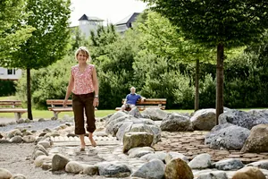 Eine Frau läuft den Barfußweg im Kurpark Bad Wörishofen, der fußläufig vom Ringhotel Sonneck entfernt liegt.