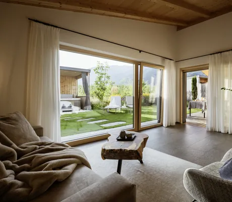 Wohnbereich im Amolaris mit Wolldecke auf dem Sofa und Blick auf den Outdoor-Whirlpiool