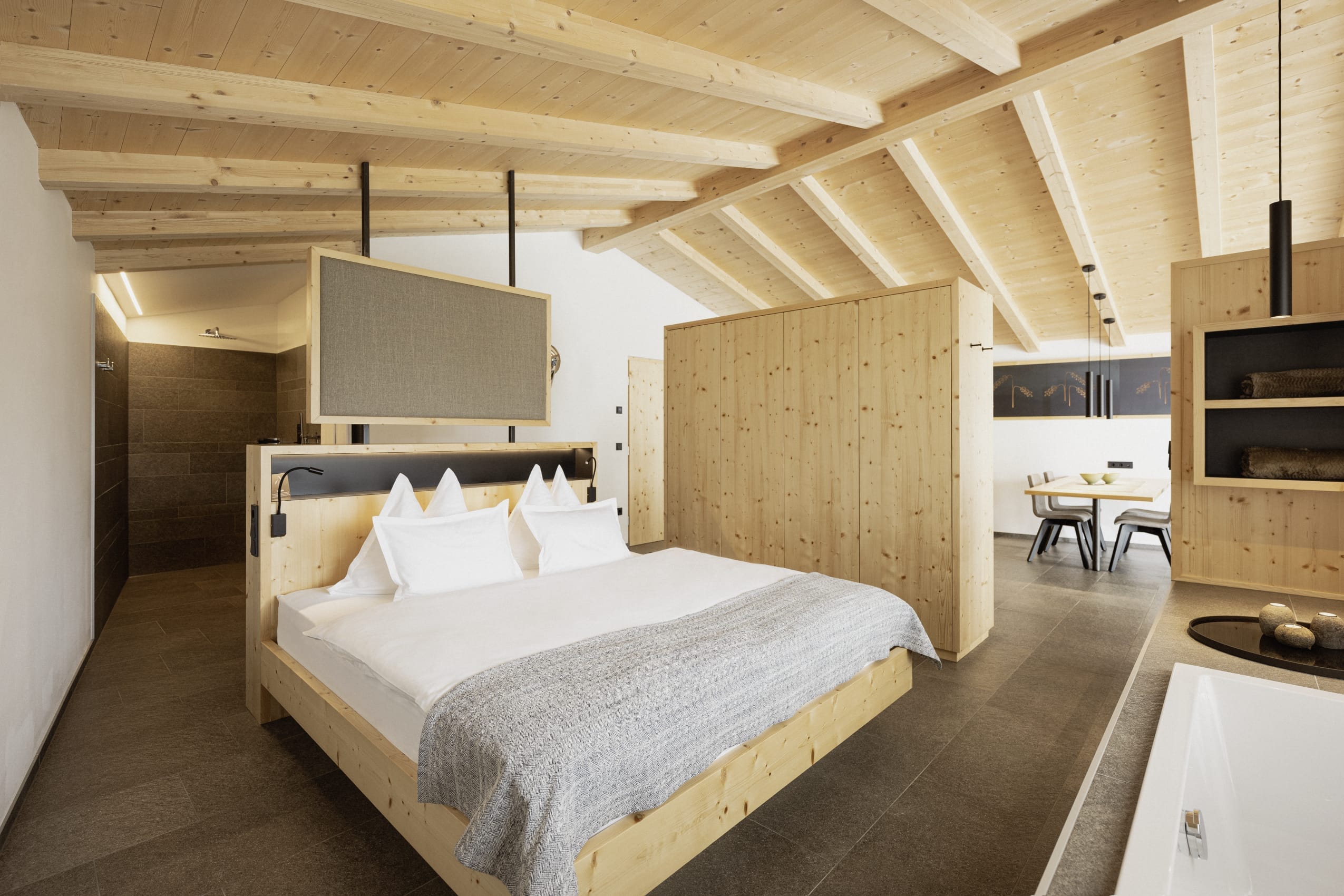 Doppelbett im Schlafbereich des Amolaris Chalets mit Naturmaterialien und heller Holzdecke.