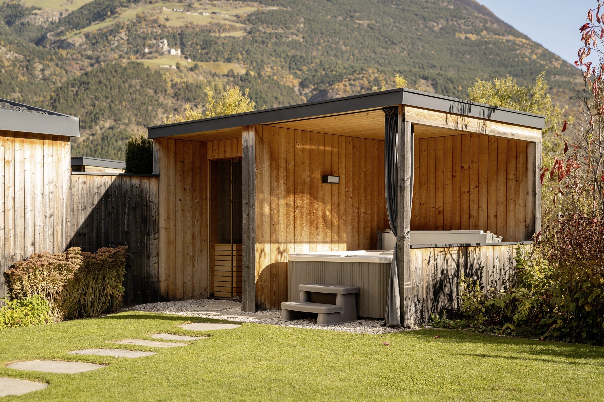 Lodge im Amolaris mit überdachtem Whirlpool und Sauna auf der Wiese.