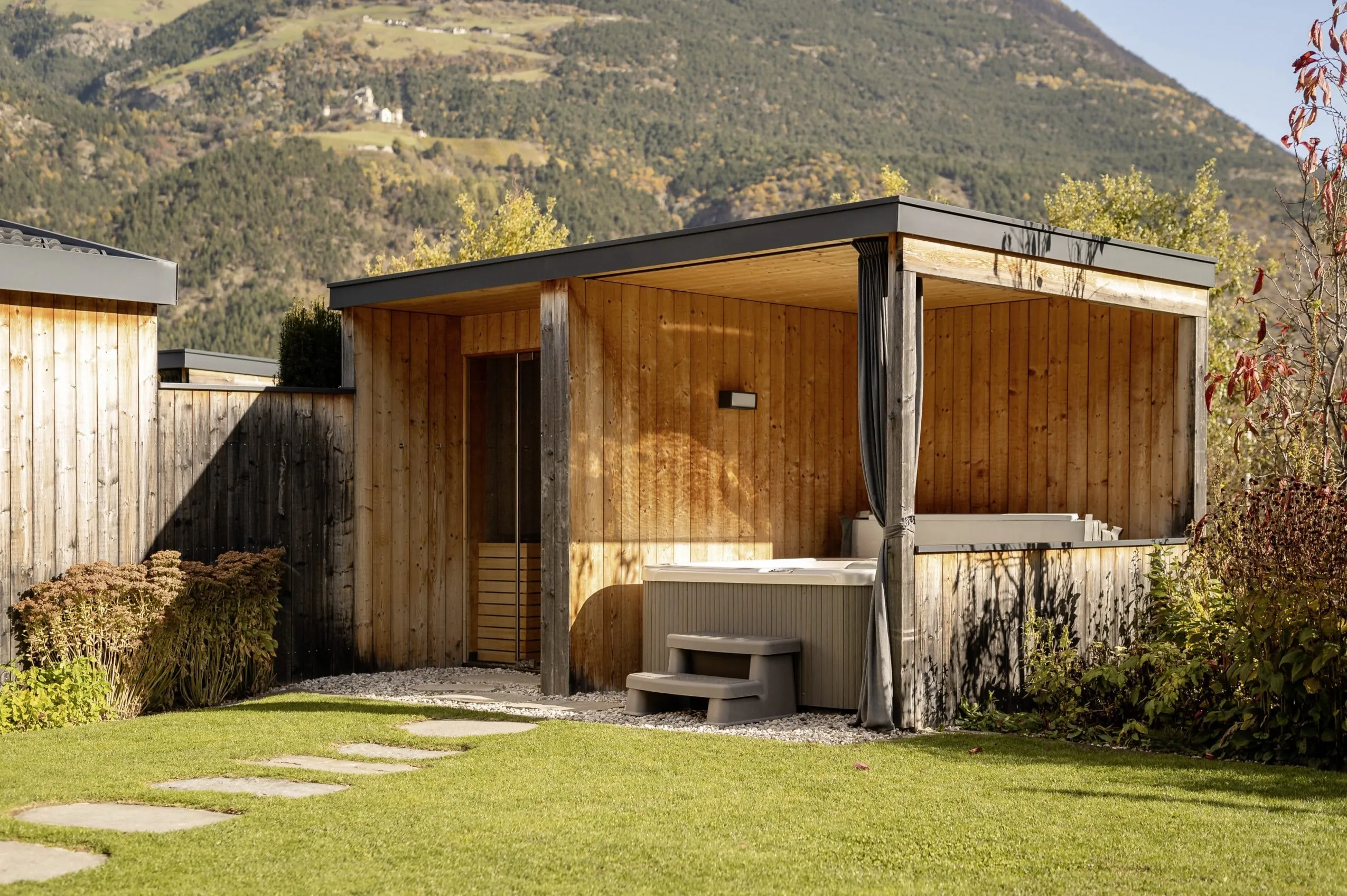 Lodge im Amolaris mit überdachtem Whirlpool und Sauna auf der Wiese.