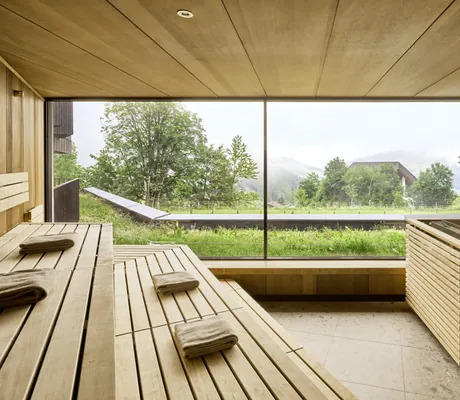 Holzsauna mit großen Panoramafenstern und Blick ins Grüne im Falkensteiner Family Hotel Montafon