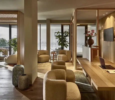 Moderne Spa-Rezeption mit Holzdesign, gemütlichen Sitzbereichen und großen Fensterfronten im Falkensteiner Family Hotel Montafon